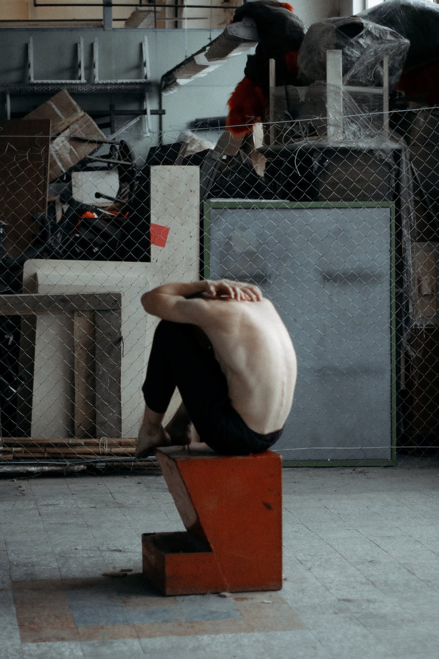 topless man sitting on brown and black block